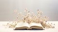 A book with white flowers bursting out of it. The book is open on a white surface, and the background is light grey. The Royalty Free Stock Photo