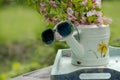 Book on the white vintage table with vase and sunglasses on green grass on sunny summer day, soft focus. Lawn with spring flowers Royalty Free Stock Photo