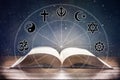 Book on wooden table with religious symbology and universe background