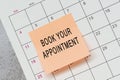 Book your appointment text on sticky note and stuck to a calendar background. Royalty Free Stock Photo