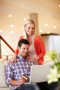 Booking a second honeymoon. A handsome man sitting on the couch with his laptop holding a credit card while his wife