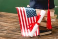 Books, academic cap, diploma and american flag on wooden surface Royalty Free Stock Photo