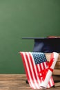 Books, academic cap, diploma and american flag on wooden surface Royalty Free Stock Photo