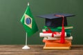 Books, academic cap, diploma and brazilian flag on wooden surface Royalty Free Stock Photo