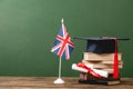 Books, academic cap, diploma and british flag on wooden surface Royalty Free Stock Photo