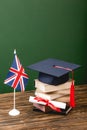 Books, academic cap, diploma and british flag on wooden surface Royalty Free Stock Photo