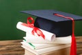 Books, academic cap and diploma on wooden surface Royalty Free Stock Photo