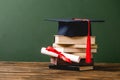 Books, academic cap and diploma on wooden surface