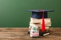 Books, academic cap and piggy bank on wooden surface Royalty Free Stock Photo