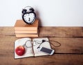 Books, alarm clock, notepad, cellphone and apple on wooden background