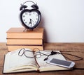 Books, alarm clock, notepad, cellphone with earphones on wooden background