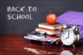 Books, apple, backpack, alarm clock and pencils on wood desk Royalty Free Stock Photo
