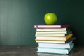 Books and apple on grey table near chalkboard. School education Royalty Free Stock Photo