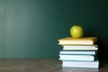 Books and apple on grey table near chalkboard. School education Royalty Free Stock Photo