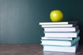 Books and apple on grey table near chalkboard. School education Royalty Free Stock Photo