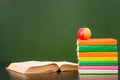 Books with apple near empty green chalkboard. Sample for text Royalty Free Stock Photo