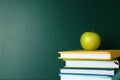 Books and apple near green chalkboard, space for text Royalty Free Stock Photo