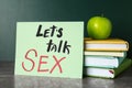 Books, apple and sign with phrase `Let`s talk sex` on grey table Royalty Free Stock Photo