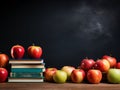 Books and apples on a wooden table in front of a blackboard
