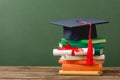 Books, diploma with ribbon and academic cap on wooden surface Royalty Free Stock Photo