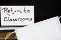 Books, Face Mask, and Return to Classrooms note with black background