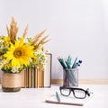 Books, glasses, markers and a bouquet of flowers in a vase on white board background. Concept for teachers day and first September