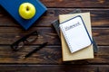 Books for homework on dark wooden student desk top-down