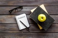 Books for homework on dark wooden student desk top-down