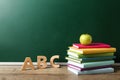 Books, letters and apple on wooden table near chalkboard, space for text. Teacher`s day Royalty Free Stock Photo