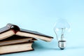 Books and light bulb on blue background close up