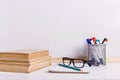 Books, markers, notebook, pencil and glasses on the table against the background of a white board. Copy space Royalty Free Stock Photo