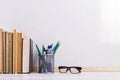 Books, markers, notebook, pencil and glasses on the table against the background of a white board. Copy space Royalty Free Stock Photo