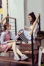 Joyful good-looking girls showing each other cards while sitting