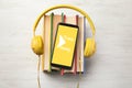 Books with modern headphones and smartphone on wooden background, top view Royalty Free Stock Photo