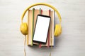 Books with modern headphones and smartphone on wooden background, top view. Space for design Royalty Free Stock Photo