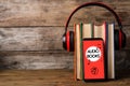 Books with modern headphones and smartphone on table. Space for text