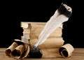 Books, old paper and feather in an inkwell isolated on a black background Royalty Free Stock Photo