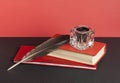 Books and quill pen with inkwell on black table on background of red wall. Free copy space. Education concept. Royalty Free Stock Photo