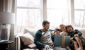 Books, reading and couple with children on couch for storytelling time in living room of happy home. Love, learning and