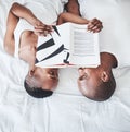 Books, reading and overhead with a black couple in bed, lying together in the morning in their home. Read, book or love Royalty Free Stock Photo