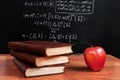 Books and red apple on a wooden table in math class in the classroom Royalty Free Stock Photo