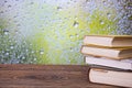 Books on an retro wooden table on a rainy day window background Royalty Free Stock Photo