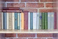 Books on a shelf against a brick wall