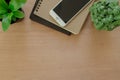 Books, smartphone, and tree pot on rustic brown wooden desk. Lifestyle workspace, top view. Royalty Free Stock Photo