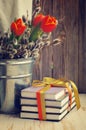 Books and a spring bouquet of tulips and branches of a willow