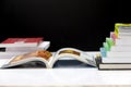 Books stacked neatly on a white table on a black background. A playbook was opened