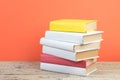 Books stacking. Books on wooden table and orange background. Back to school. Copy space for ad text