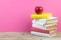 Books stacking. Books on wooden table and pink background. Back to school. Copy space for ad text