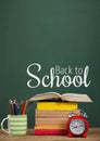 Books on the table against green blackboard with back to school text