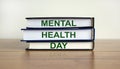 Books with the text `mental health day` on beautiful wooden table, white background. Concept. Copy space